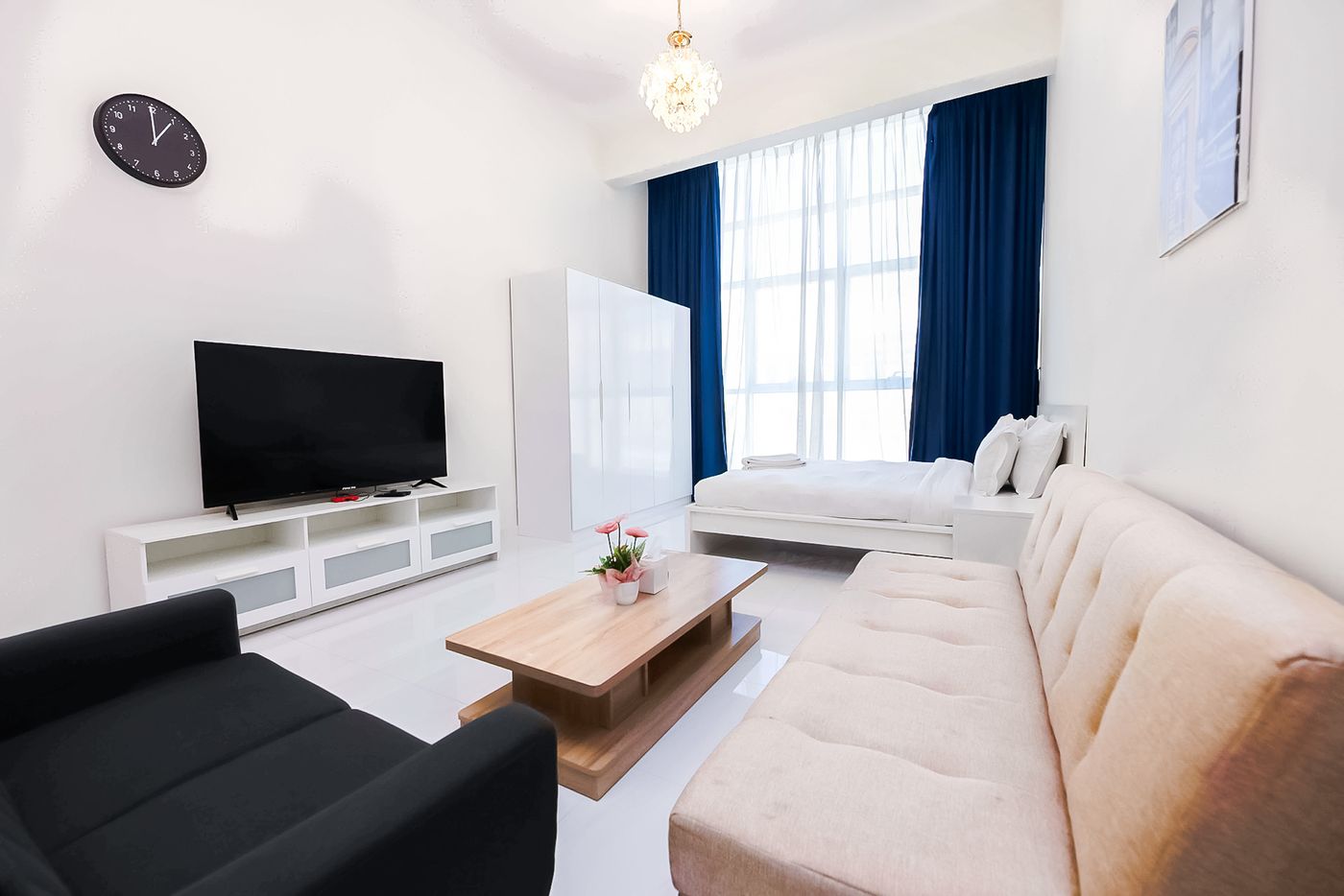 Family apartment living area with a sofa bed, a TV and a bed by a tall window