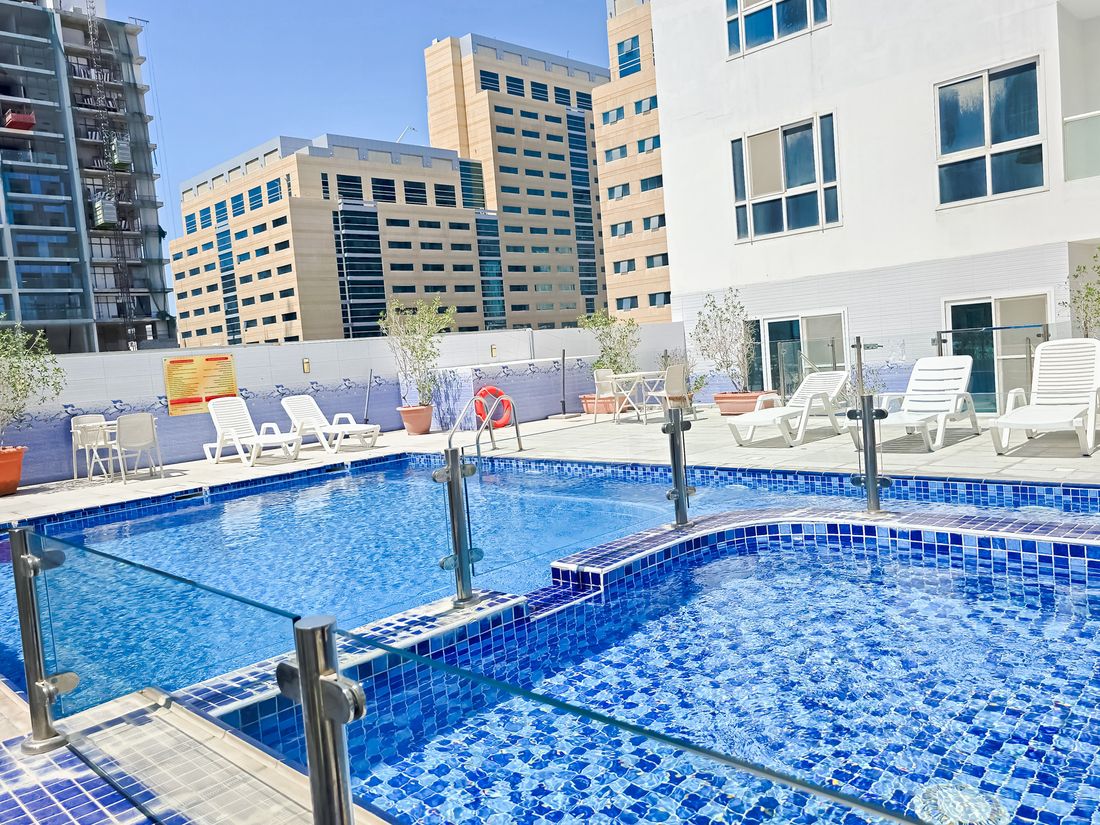 Swimming pool with blue mosaic tiles and white sun loungers